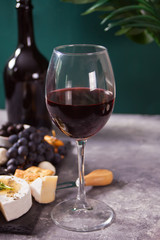 glass of red wine and plate with assorted cheese, fruit and other snacks for party