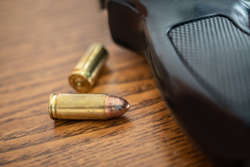 Fototapeta na wymiar Close-up of 9mm pistol gun handle, focus on bullets on the table