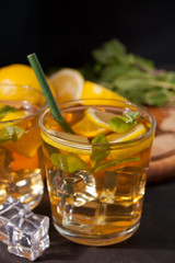 Two glasses of cold refreshment tea with ice and lemon fruit.