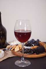 glass of red wine and plate with assorted cheese, fruit and other snacks for party