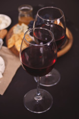 Two glass of red wine and plate with assorted cheese, fruit and other snacks for party