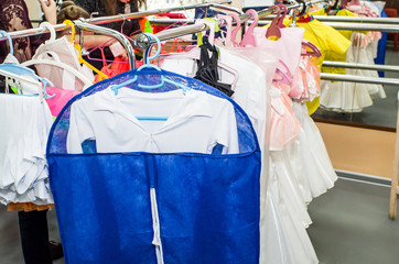 A row of stage costumes for upcoming performances by dance actors hangs on a floor hanger.