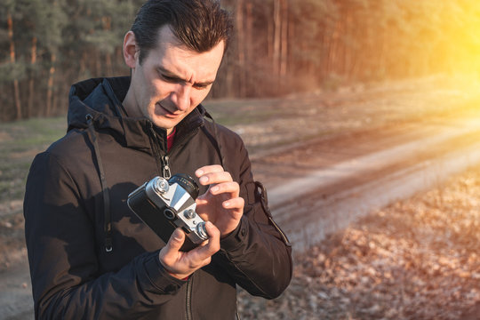 man takes pictures on an old mechanical camera on a background of nature