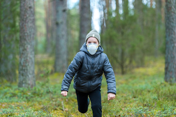 Little boy with a mask run in the forest. Corona virus quarantine