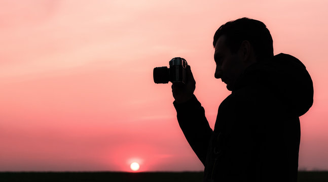 silhouette of a man who takes pictures with an old mechanical camera on a sunset background