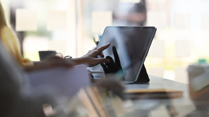Cropped image of Designer woman's hand using a stylus pen to drawing on computer tablet with keyboard case that putting on white working table over comfortable office as background.