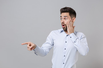 Shocked young unshaven business man in light shirt posing isolated on grey background. Achievement...
