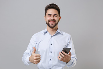 Smiling young unshaven business man in light shirt posing isolated on grey background in studio....