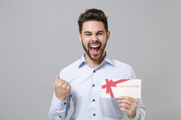 Overjoyed young unshaven business man in light shirt posing isolated on grey background....