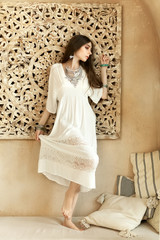 Fototapeta premium Beautiful girl in white dress and stylish jewelry inside room middle eastern interior