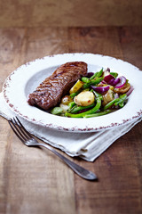 Beef steak with oven roasted vegetables on rustic wooden background.