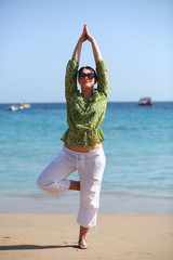 Portrait of a caucasian 35 year old woman doing yoga at the sea shore
