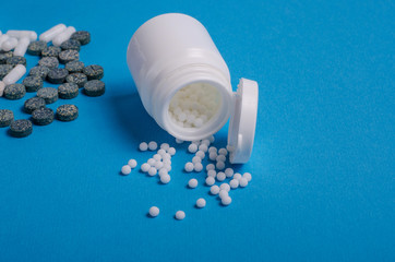 Dietary supplements in capsules and tablets and homeopathic granules on a blue background with copy...