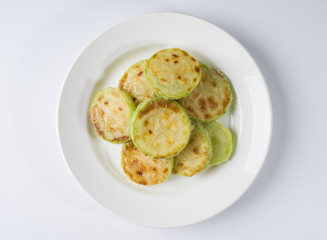 Fried young zucchini on a white plate. View from above