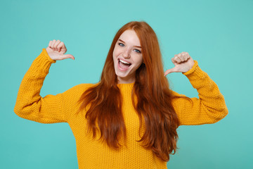 Excited young redhead woman girl in yellow sweater posing isolated on blue turquoise wall...