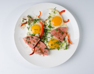 Fried sausage fried eggs on a white round plate. Top view