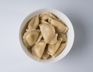 Freshly boiled dumplings in a white bowl. Top view