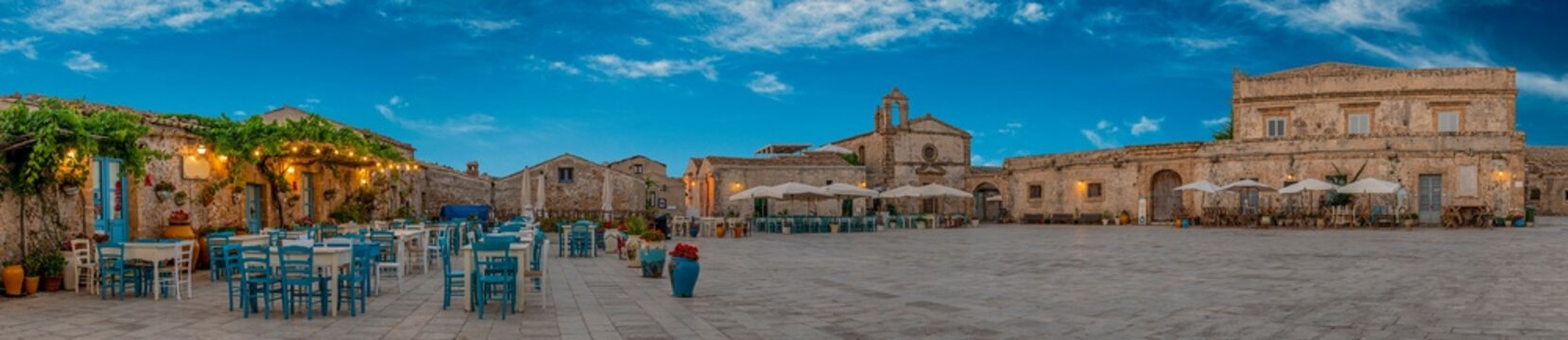 Panoramic view of the picturesque sicilian village Marzamemi, view of the traditional outdoor cafe and the church and the central square, province of Syracuse, Sicily, southern Italy