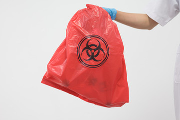 Scientist wearing blue gloves and red bag with bioharzard sign.A woman worker hand holding red...