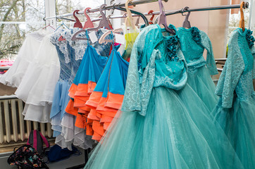 A row of stage costumes for upcoming performances by dance actors hangs on a floor hanger.