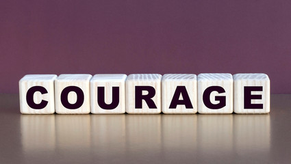 COURAGE word on cubes on a burgundy background