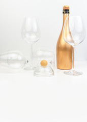 Creative composition with marzipan dessert, glass goblets and a golden bottle of champagne.