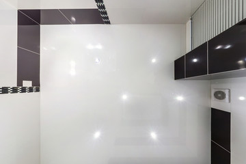 suspended ceiling with led lightspot lamps and drywall construction in empty room in apartment or house. Stretch ceiling white and complex shape. looking up