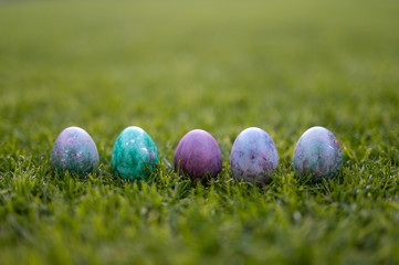 Colored easter eggs lying in a row on the grass