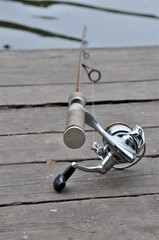 fishing rod on a wooden boardwalk.Fishing on a lake on a rainy morning with gray clouds. Fishing rod in the water on a wooden pier.men's hobby