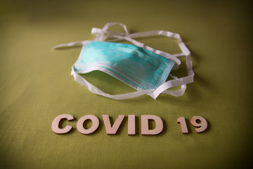 Mask on a green background with the word Covid 19 which means Coronavirus