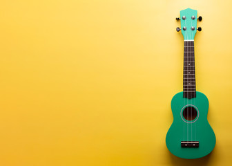 Green ukulele on a yellow background. Little Ukulele. 