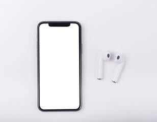 White wireless bluetooth earphones or headphones and smartphone over white background. Close up....