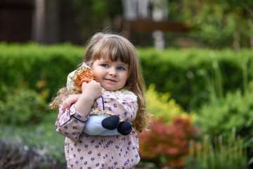 little girl with a doll. little girl with a flower. little girl playing with a doll in the park