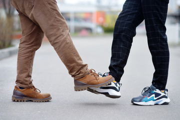 Two men greeting each other with foot instead of handshake. Friends or colleagues touch feet....