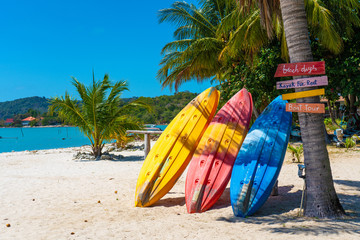 Obraz na płótnie Canvas Multi-colored kayaks on a tropical sandy beach. Kayak rental. Tourist entertainment