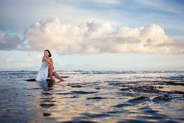 Beautiful woman by the ocean at sunset