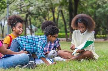 Fototapeta premium Happy fun group of African American children practice drawing in a book and sitting in the park. Education outdoor concept.