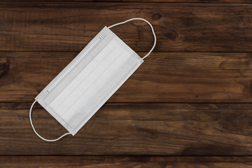 disposable mask against the virus, on wooden background