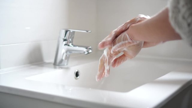 Persona lavando las manos para desinfectar y prevenir la infecci&oacute;n de corona virus con agua y jab&oacute;n en el ba&ntilde;o 4k