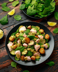 Salmon, new potato, courgette and spinach salad on wooden table