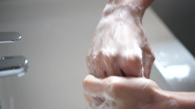Persona lavando las manos para desinfectar y prevenir la infecci&oacute;n de corona virus con agua y jab&oacute;n en el ba&ntilde;o 4k