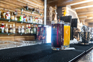 Multi-colored cocktails and soft drinks on a bar counter in glass glasses