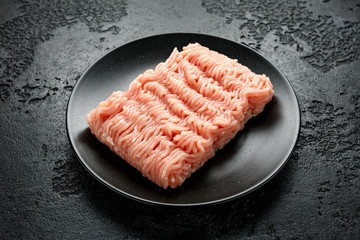 Raw Turkey breast fillets minced meat on black plate ready to cook