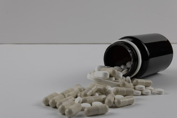 Mixture of drugs coming out of a bottle up close on a white background