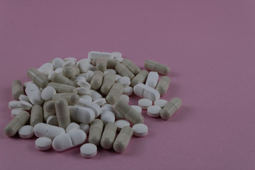 A bunch of colored pills mixed together on a pink background. Mixed, pain.