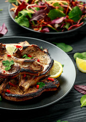 Homemade Grilled Pork loin chops in lemon sauce with herbs on rustic wooden table