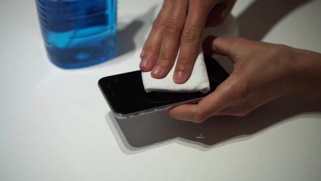 Persona limpiando tel&eacute;fono m&oacute;vil durante la cuarentena en casa para desinfectar y prevenir la infecci&oacute;n de corona virus 4k