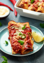 Baked Chicken fillets enchiladas with courgette, salsa sauce and cheese served with lemon wedges and chilies