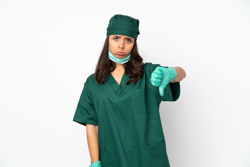 Surgeon woman in green uniform isolated on white background showing thumb down with negative expression