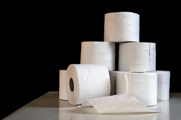 Several rolls of toilet paper, shortage in Germany after shoppers panic buying because of coronavirus pandemic outbreak, dark background with copy space